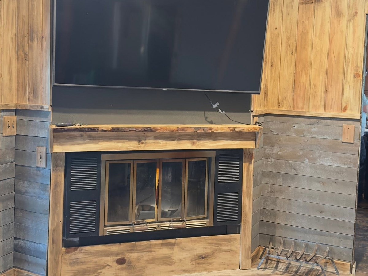 The rebuilt fireplace clad in wood with a mounted television above