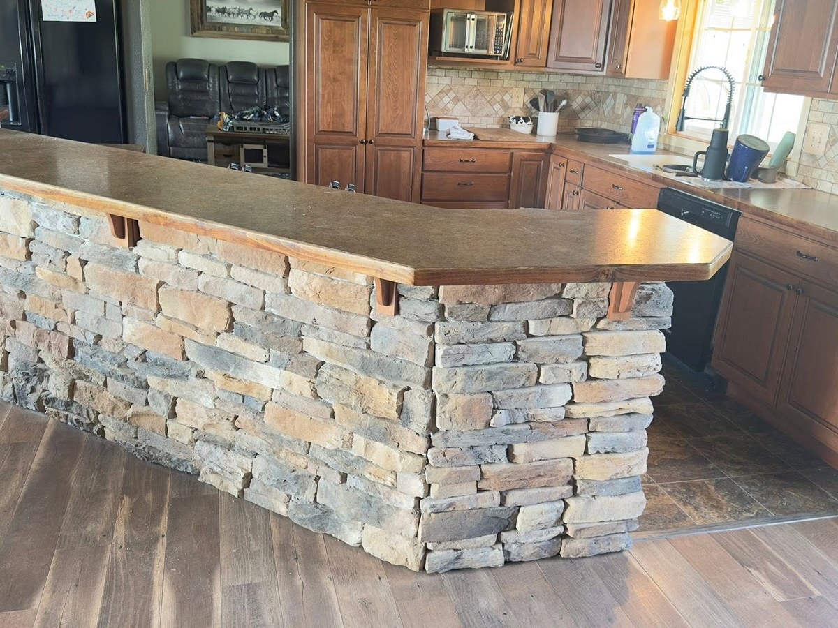 Kitchen island with a stacked stone base and a raised bar top