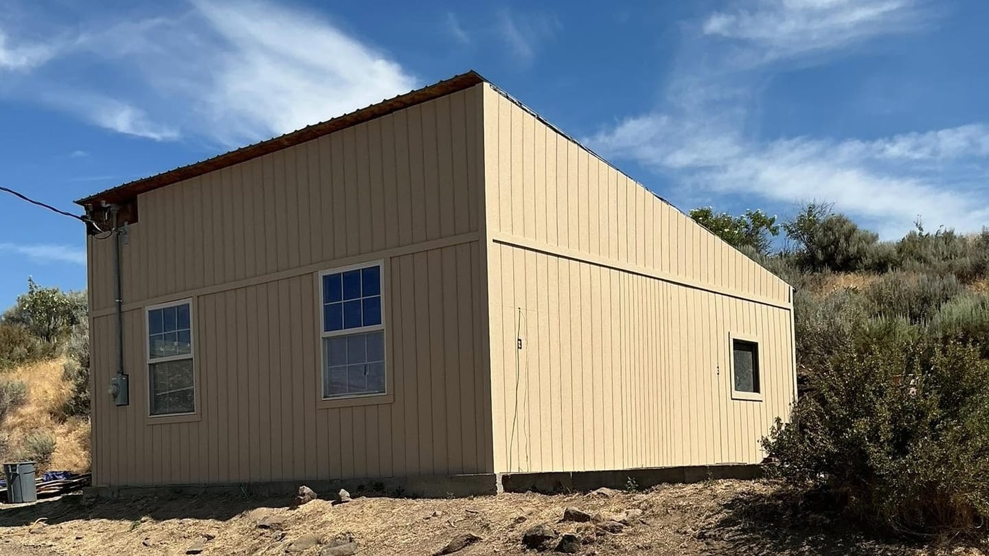 Restored rural garage clad in new tan steel siding