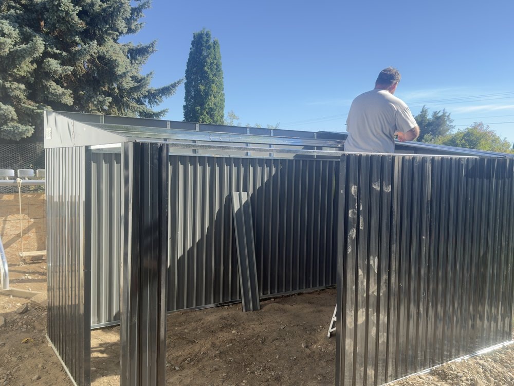 Someone working along the top rail while spare panels lean inside the open shell