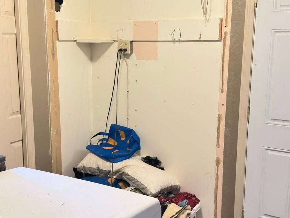 Closet opening with the trim stripped off, torn drywall edges, loose wiring, and a shelf still in place