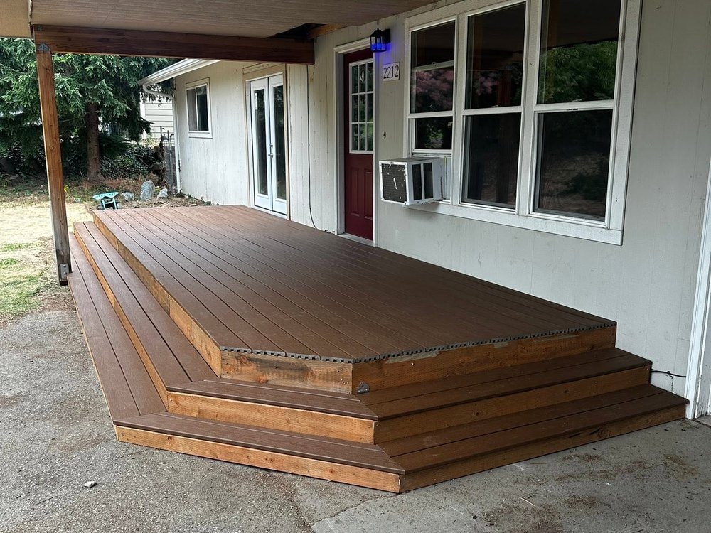 Finished deck boards and wrapped steps running under the roof overhang to the red door