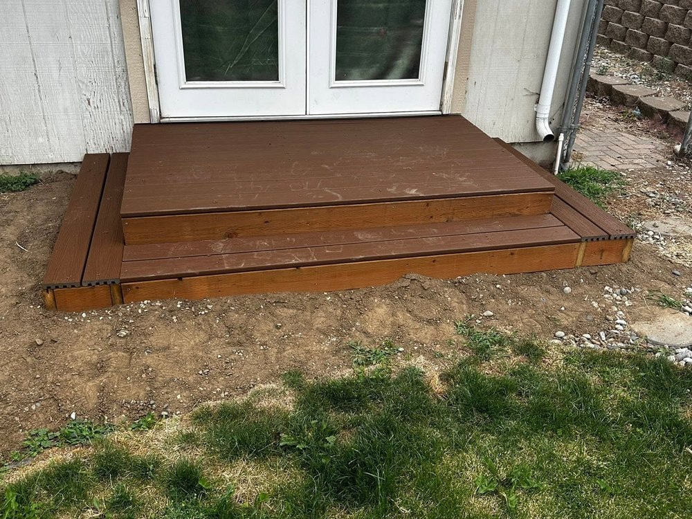 Finished landing with a single step wrapping the corner at the French doors, downspout at right