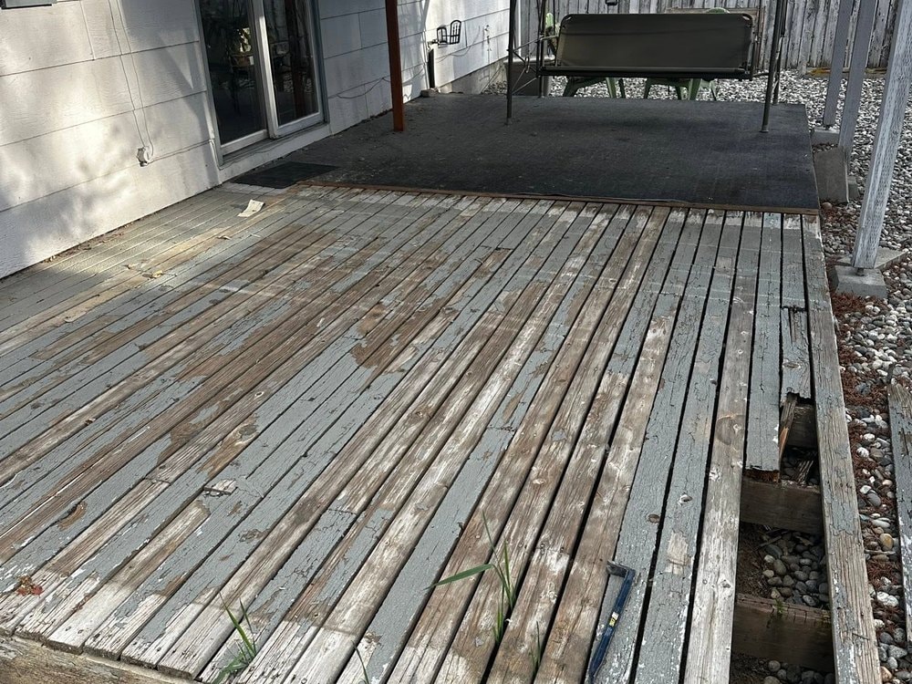 Weathered deck boards with peeling gray paint running up to the sliding glass door