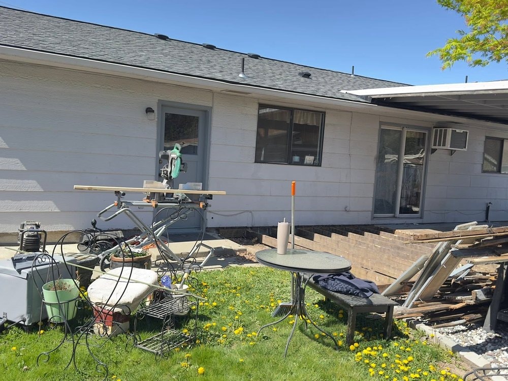 Miter saw set up in the yard beside the deck stripped back to its framing