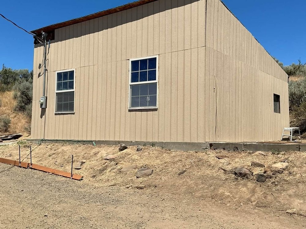 The finished garage in new tan steel siding, long wall