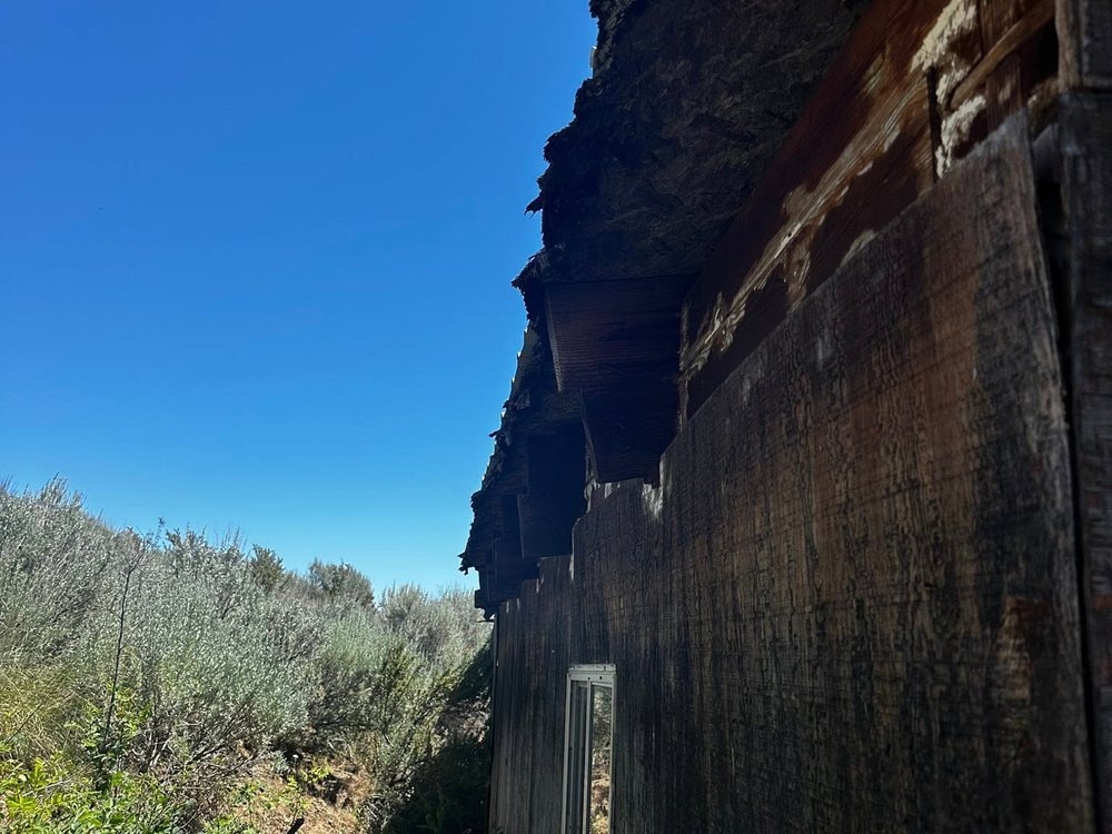Failing eave and split siding boards on the old structure, seen from below