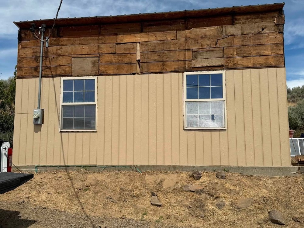 New tan steel siding going on the lower walls with the old wood band still exposed above