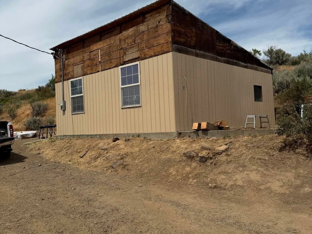 The building part way through re-siding, seen from the approach road