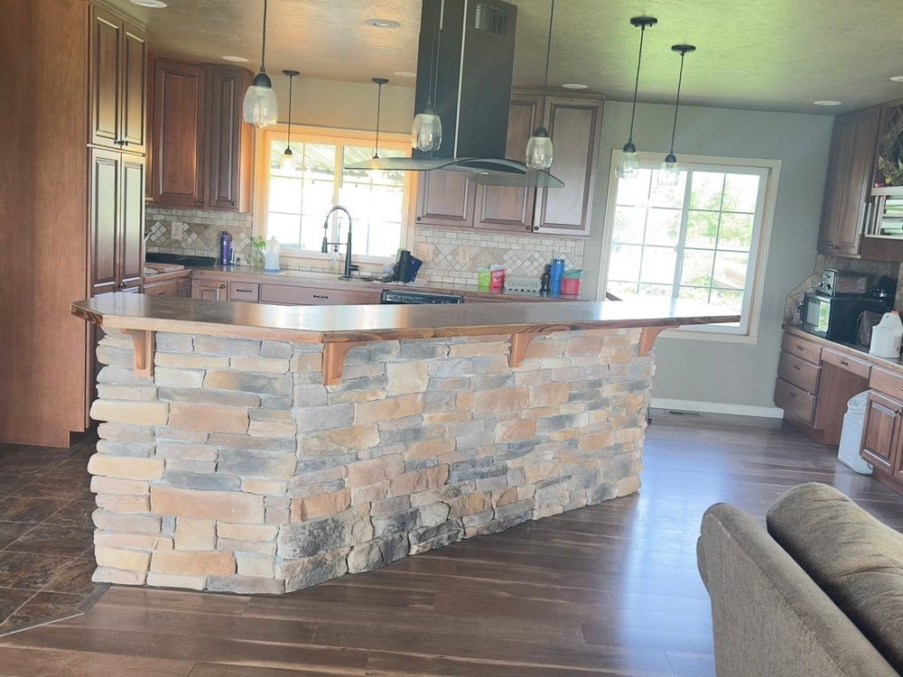 Stone bar dividing the kitchen from the living room, wood counter running along its top