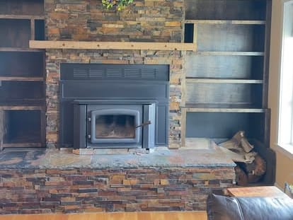 Interior wall and built-in shelving beside a stone fireplace