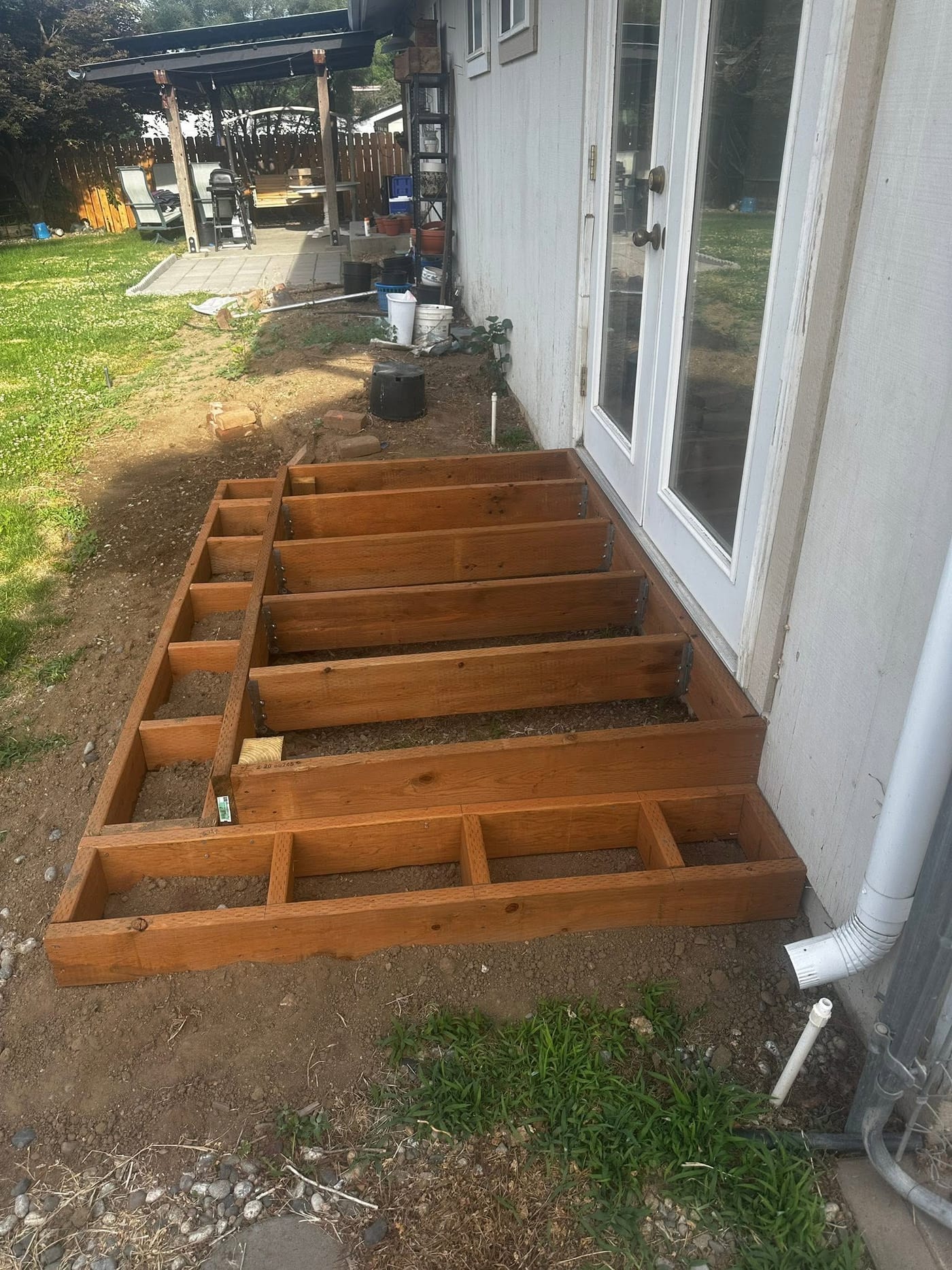 Framing for a small landing deck at a French door, with the downspout run clear