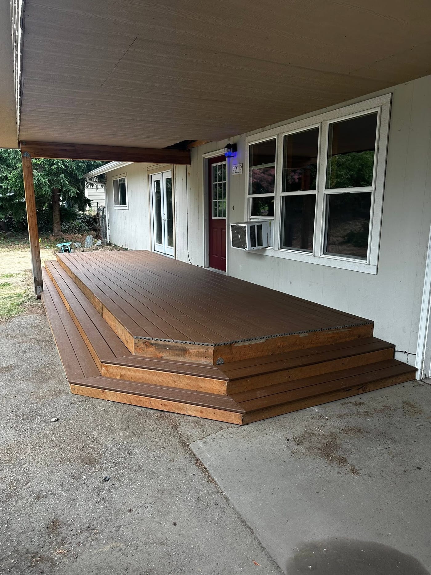 The same covered deck finished, with stained boards and a full-width step