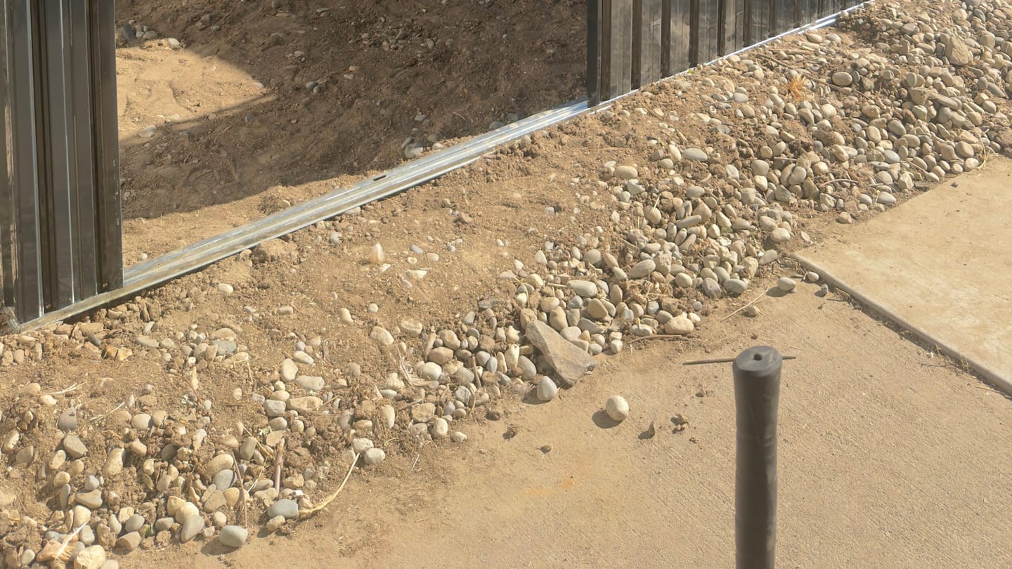 Corrugated metal fence panels being set along a property line in Central Washington