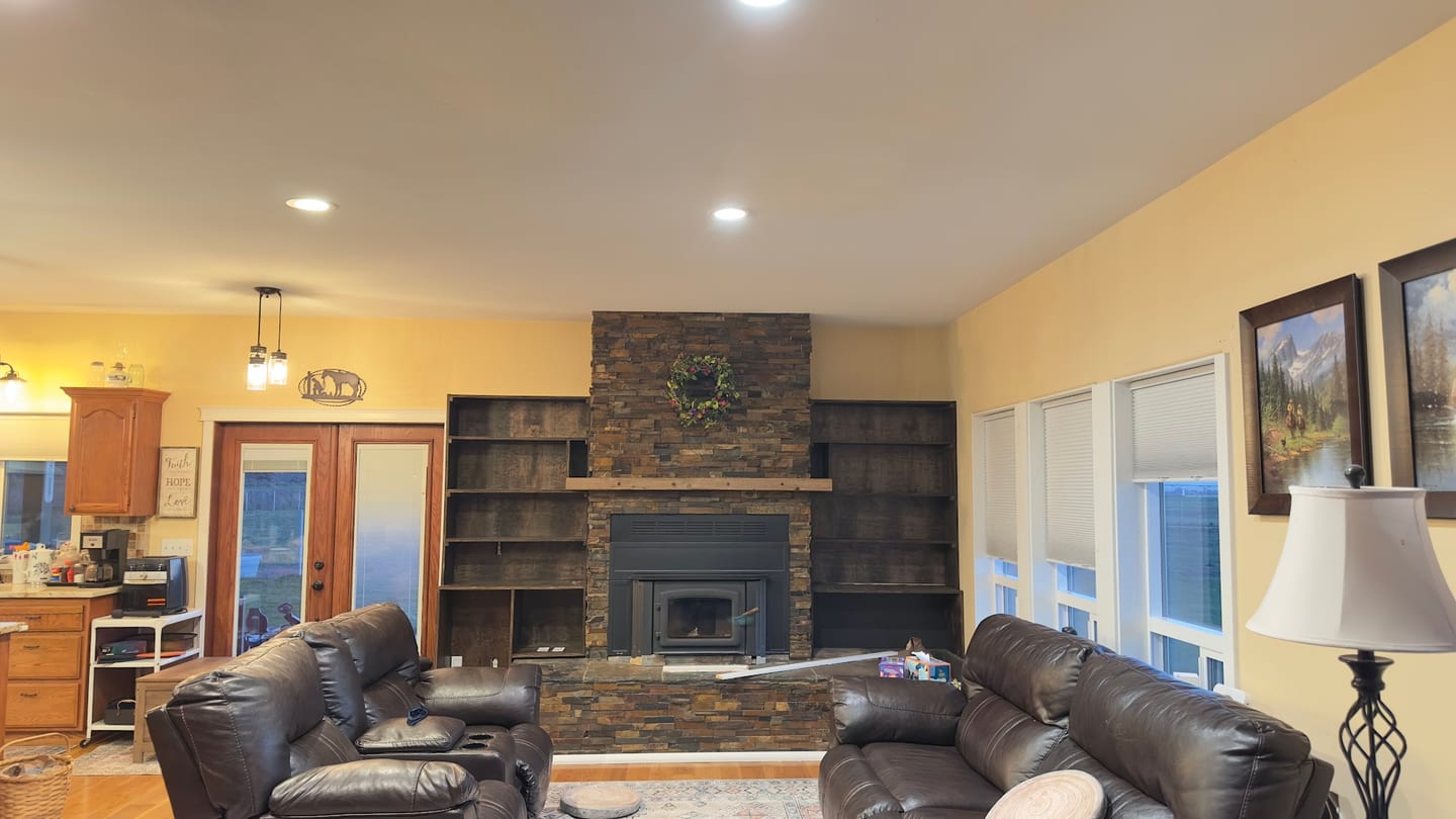The finished stone fireplace flanked by dark wood built-in shelving