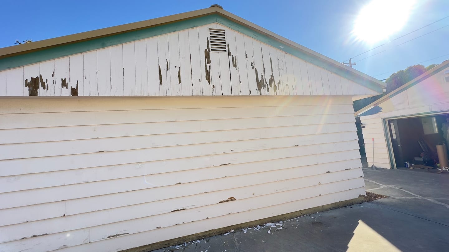 Lap siding with peeling paint and weather damage before repair