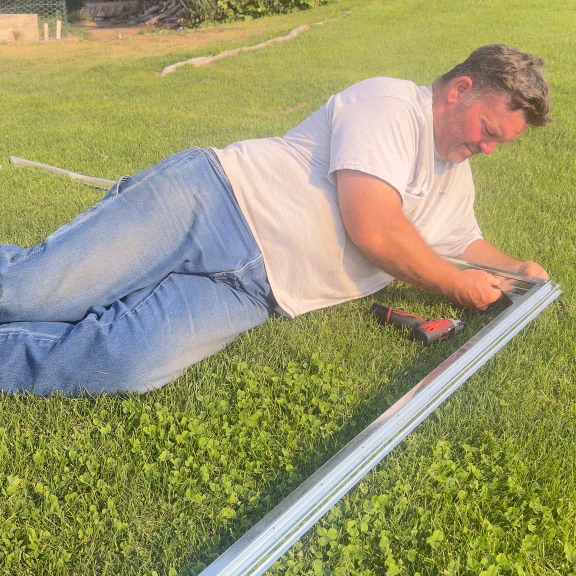 TJ lying flat on the grass to fasten a rail